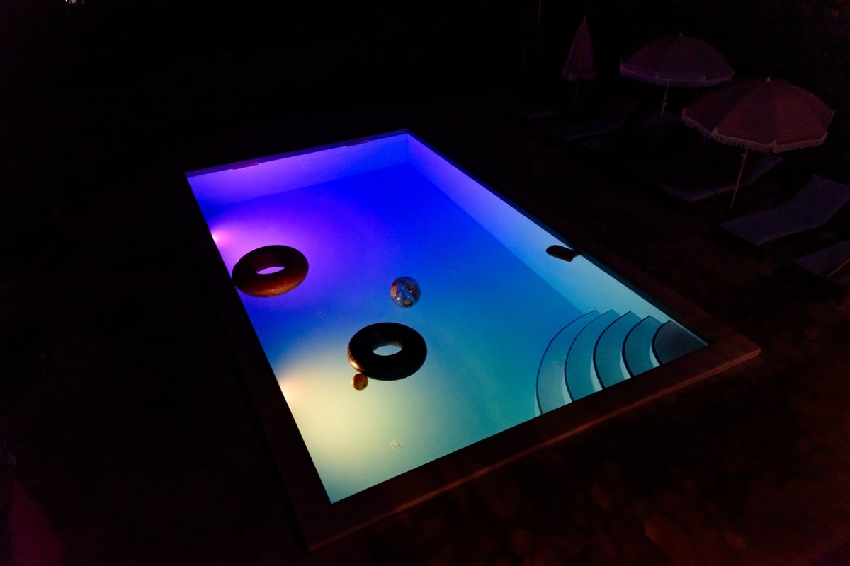 Piscina iluminada de noche con luces subacuáticas