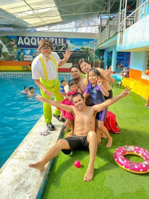 Swim instructor with group of children posing happily at indoor aquatic center pool deck