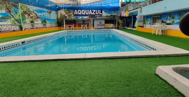 Piscina interior en las instalaciones de Aquazul con marcadores de carriles, césped artificial alrededor y señalización azul arriba